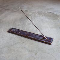Incense holder with a single incense stick on a textured surface