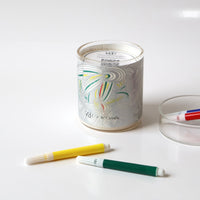 Candle with colorful wick trimmer and ashtray on a white background