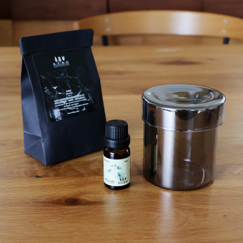 Black bag of biochar, small bottle, and metal container on a wooden table
