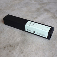 Black candle box with a label on a gray surface