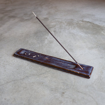 Incense holder with a single incense stick on a textured surface