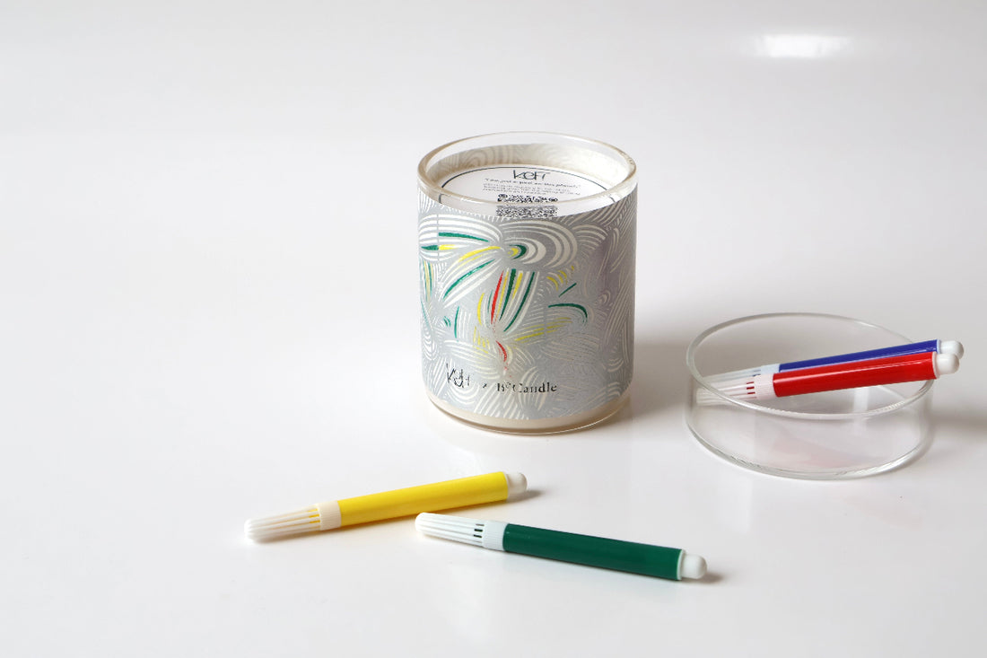 Candle with colorful wick trimmer and ashtray on a white background