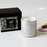 Candle with decorative packaging on a white surface