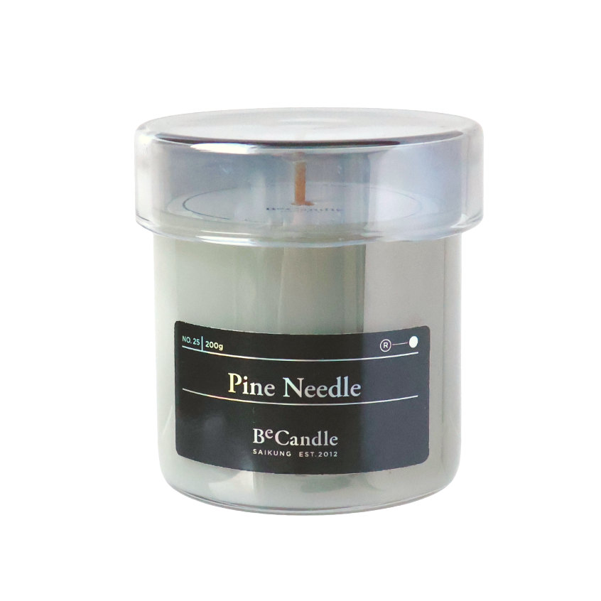 Candle in a clear container with a black label on a white background