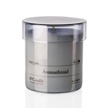 Candle in a clear container with 'Aromathread' branding on a white background