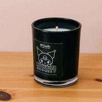 Black Kuromi candle with a label on a wooden surface