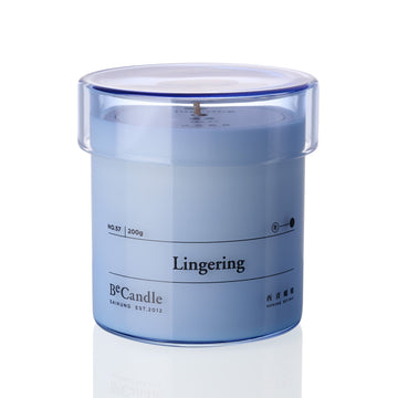 Blue candle in a transparent container labeled 'Lingering' by B&Candle on a white background